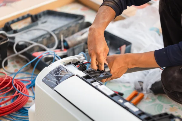 Technician repairing electrical controls in a compact air conditioning unit